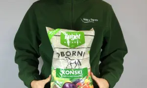 Osoba w zielonej bluzie trzyma worek z napisem "Obornik koński granulowany". Produkt jest naturalny i przeznaczony do ogrodu.