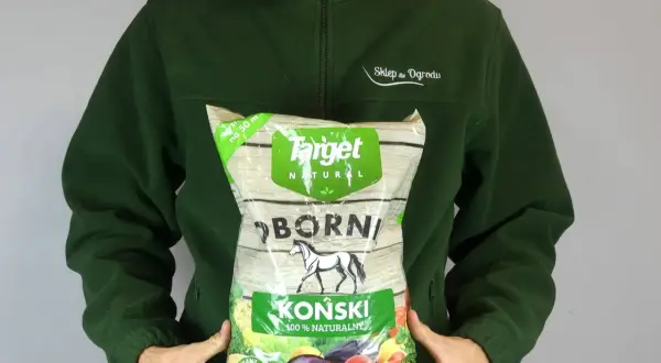 Osoba w zielonej bluzie trzyma worek z napisem "Obornik koński granulowany". Produkt jest naturalny i przeznaczony do ogrodu.
